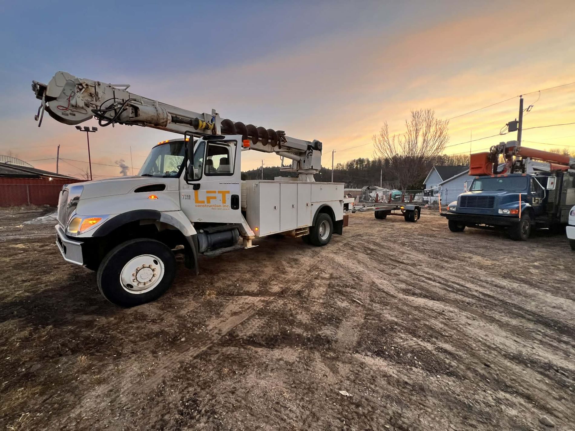 Camions de LFT Construction sur un chantier au coucher de soleil