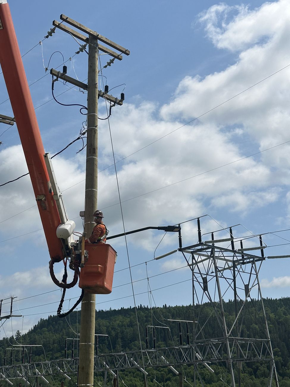 Monteur de LFT en nacelle sur une ligne aérienne près d'un poste électrique